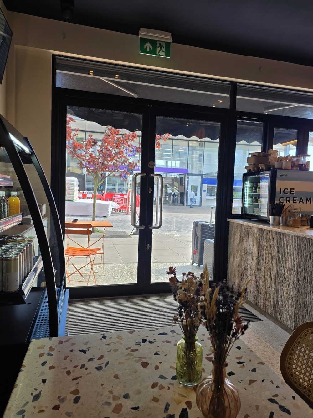 A terrazzo table with a dried-flower vase, looking out through the glass doors to the street.