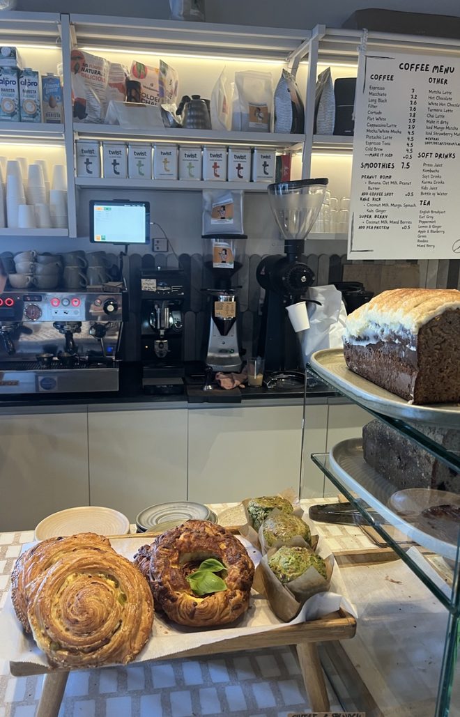 The back-bar coffee machine and retail shelves, cropped below the menu board.