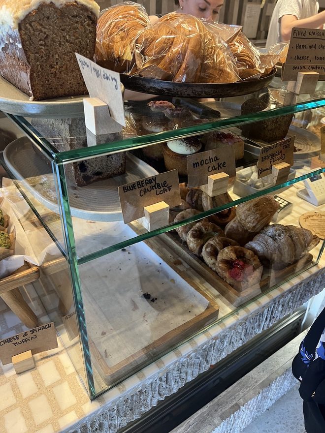 The pastry display case, croissants and loaves behind glass.