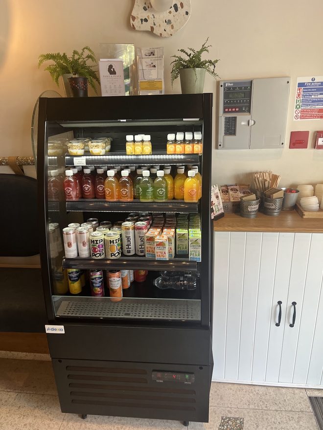 Bottled drinks in the open chiller against a white panelled wall.