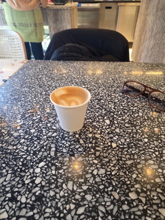 A single takeaway cup on the dark terrazzo table.