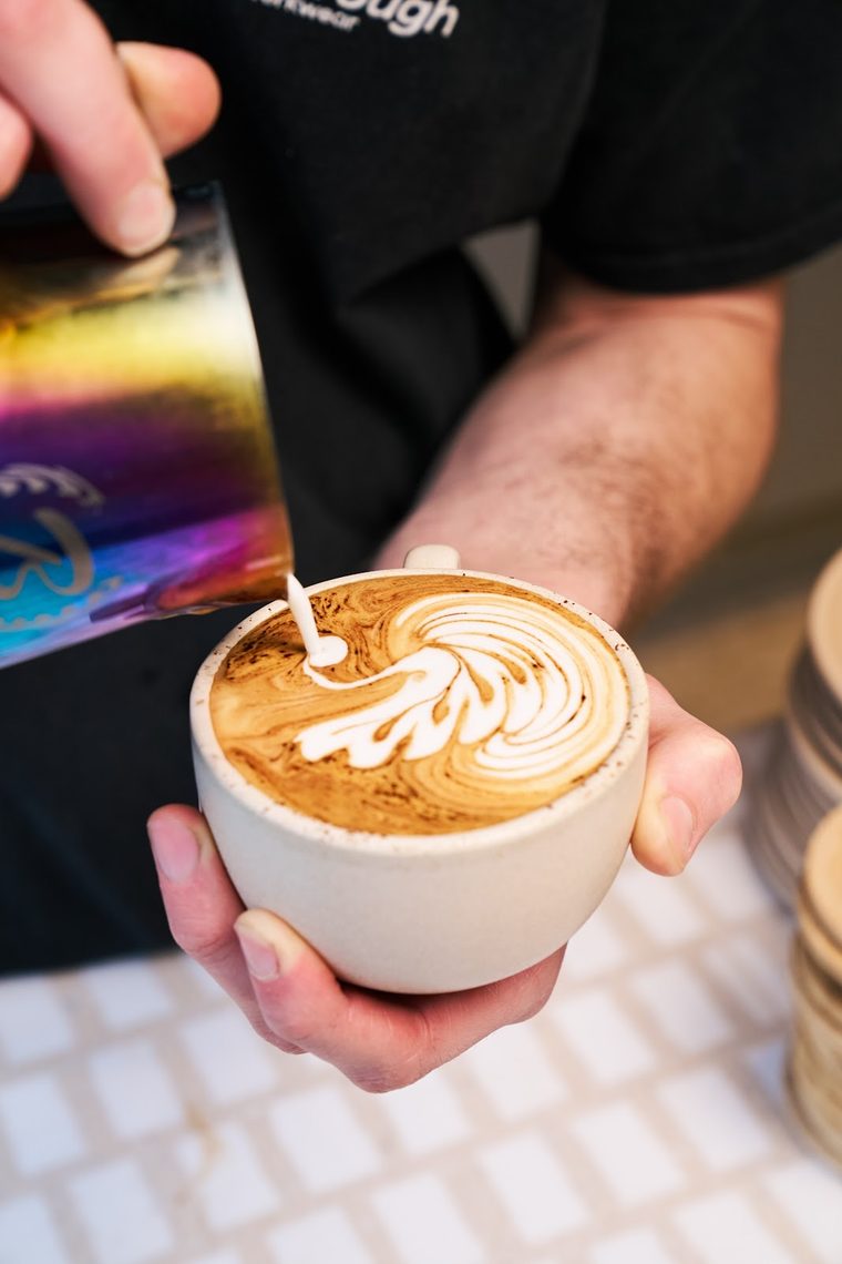 Cappuccino with rosetta latte art in a white cup.