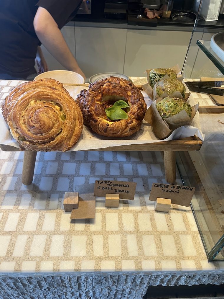 Cinnamon swirl, pistachio bun and babka on a wooden riser.