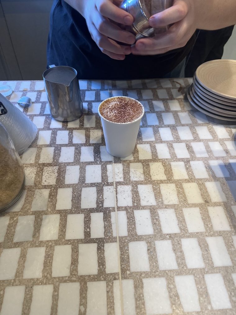 Cocoa dusted over a takeaway cup at the counter.